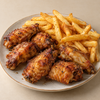 Four golden-brown crispy fried chicken wings served on a beige ceramic plate next to a side of french fries, set against a neutral beige background.