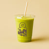 Green smoothie in a Halo Bagels Cafe cup with a straw on a beige background 
